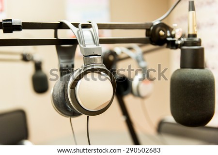 technology, electronics and audio equipment concept - close up of headphones and microphone at recording studio or radio station