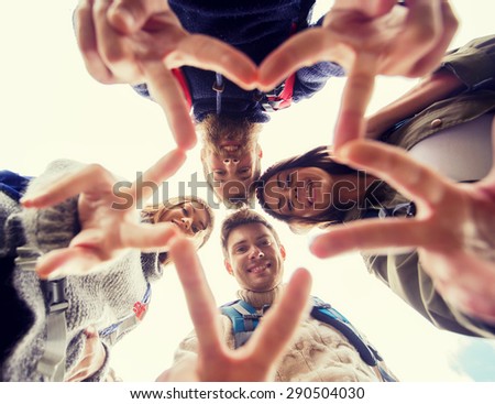 travel, tourism, hike, gesture and people concept - group of smiling friends with backpacks standing in circle and showing victory sign outdoors