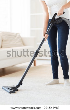 people, housework and housekeeping concept - close up of woman with vacuum cleaner cleaning carpet at home