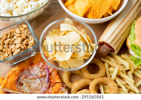 fast food and unhealthy eating concept - close up of different fast food snacks on wooden table