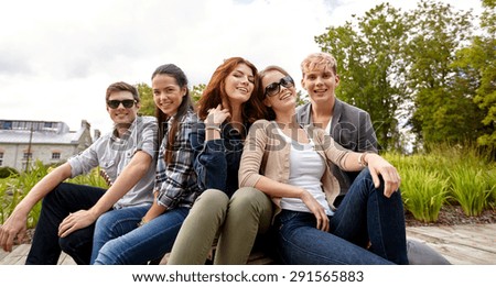 summer holidays, friendship, leisure and teenage concept - group of students or teenagers hanging out at campus or park