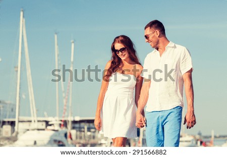 love, travel, tourism and people concept - smiling couple wearing sunglasses walking at harbor