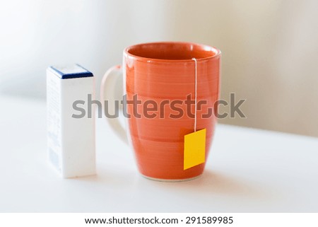 food, junk-food, drinks and unhealthy eating concept - close up of sweetener and cup with tea bag on table