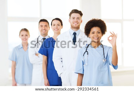 hospital, profession, people and medicine concept - group of happy doctors at hospital showing ok hand sign