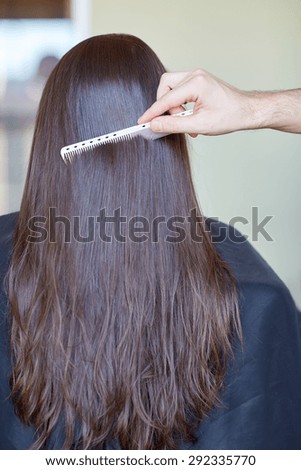 beauty, hair care, hairstyle and people concept - stylist hand with comb combing woman hair at salon