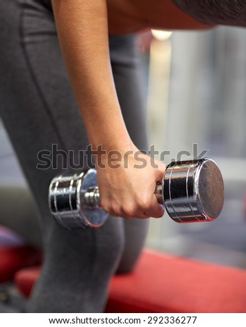 fitness, sport, exercising and weightlifting concept - close up of young woman and personal trainer with dumbbells flexing muscles in gym