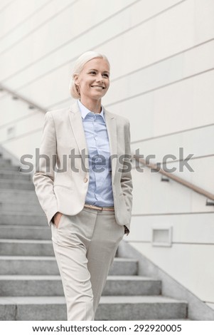 business, people and education concept - young smiling businesswoman walking down stairs outdoors