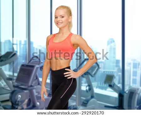 people, fitness and sport concept - happy woman fitness instructor over gym machines background