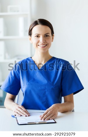 health care, profession, people and medicine concept - happy female doctor or nurse with clipboard at hospital