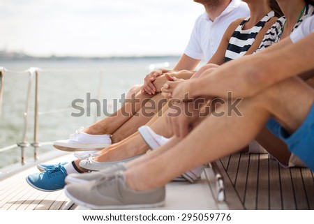 vacation, travel, sea, sailing and people concept - close up of friends legs sitting on yacht deck