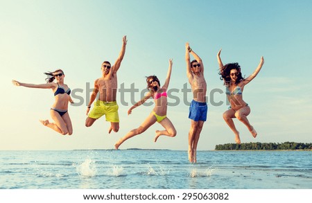 friendship, sea, summer vacation, holidays and people concept - group of smiling friends wearing swimwear and sunglasses jumping on beach