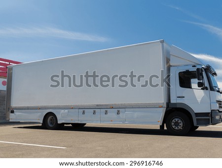 transportation, freight transport and vehicle parts concept - white truck on city parking with copy space