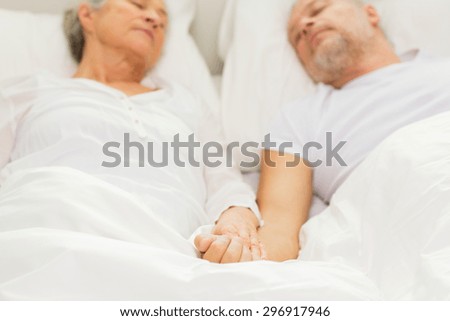 family, bedtime, resting, age and people concept - close up of senior couple lying in bad and sleeping at home