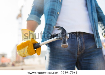 building, tools, construction and people concept - close up of builder hand in glove holding hammer