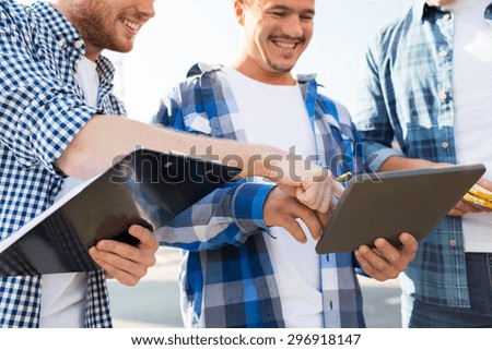 building, construction, teamwork, technology and people concept - group of smiling builders in hardhats with tablet pc computer and clipboard outdoors