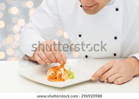 cooking, profession, haute cuisine, food and people concept - close up of happy male chef cook decorating dish over holidays lights background