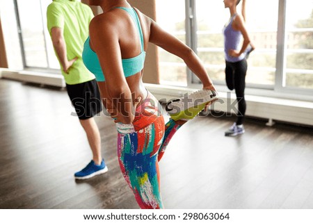 fitness, sport, training, gym and lifestyle concept - close up of people with trainer exercising and stretching leg in gym