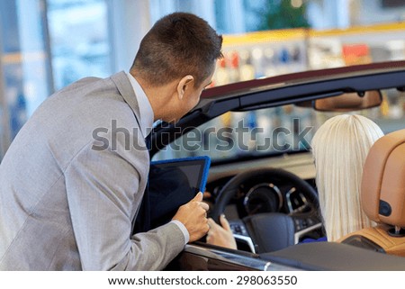 auto business, car sale, technology and people concept - woman and car dealer with tablet pc computer in auto show or salon