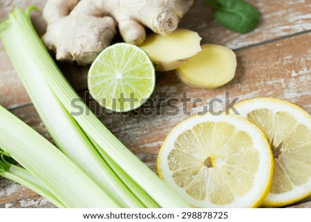 healthy eating, vegetarian food, culinary and diet concept - close up of ginger, celery and lemon on wooden table