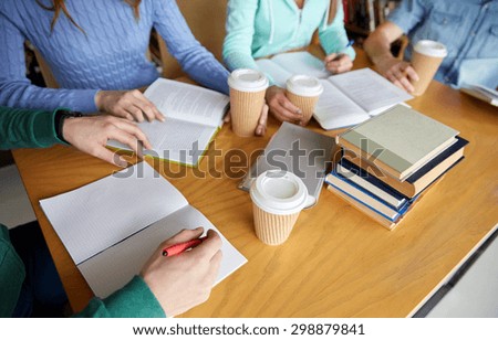people, learning, education and school concept - close up of students hands with books or textbooks writing to notebooks and drinking coffee