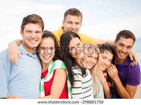 summer holidays, vacation, tourism, travel and people concept - group of happy friends hugging on beach