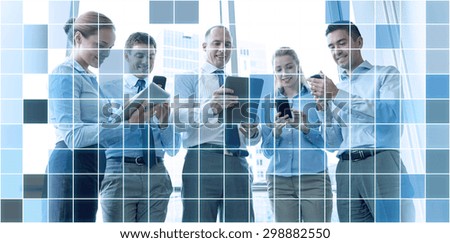 business, teamwork, people and technology concept - business team with tablet pc and smartphones meeting in office over blue squared grid background