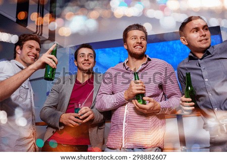 nightlife, party, friendship, leisure and people concept - group of smiling male friends with beer bottles drinking and pointing finger to something at nightclub