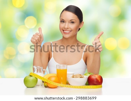 people, gesture and diet concept- happy asian woman with healthy food showing thumbs up over green lights background