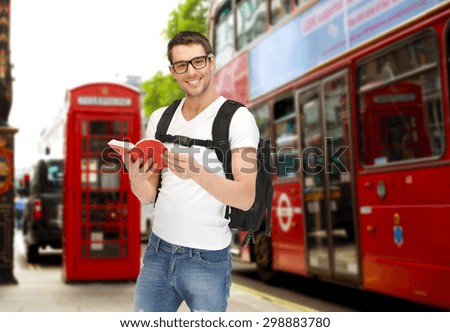 people, travel, tourism and education concept - happy young man with backpack and book over london city city bus on  street background