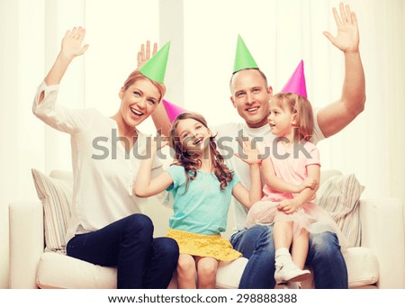 celebration, family, holidays, children and birthday concept - happy family with two chldren in hats waving hands at home