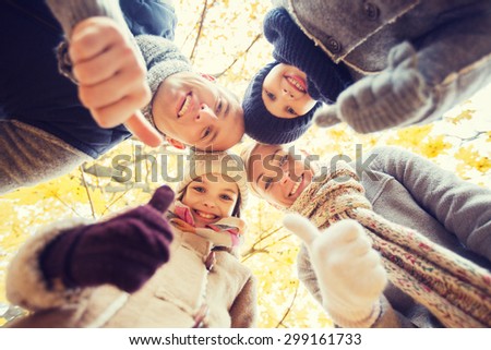 family, childhood, season, gesture and people concept - happy family showing thumbs up in autumn park