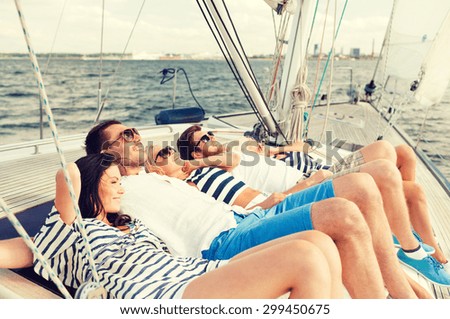 vacation, travel, sea, friendship and people concept - smiling friends lying on yacht deck