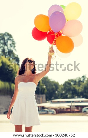 happiness, summer, holidays and people concept - smiling young woman wearing sunglasses with balloons in park