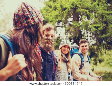adventure, travel, tourism, hike and people concept - group of smiling friends with backpacks and tablet pc computer walking outdoors