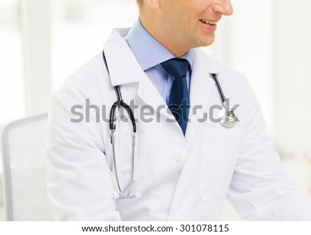medicine, health care, people and profession concept - close up of happy male doctor with stethoscope at medical office in hospital