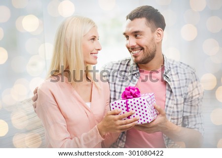 relationships, love, people, birthday and valentines day concept - happy man giving woman gift box over holidays lights background