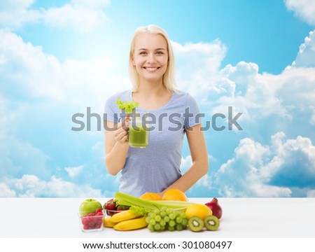 healthy eating, vegetarian food, diet, detox and people concept - smiling woman drinking green vegetable juice or shake from glass over blue sky and clouds background
