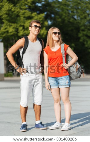 travel, summer vacation, tourism and friendship concept - smiling couple with backpacks in city