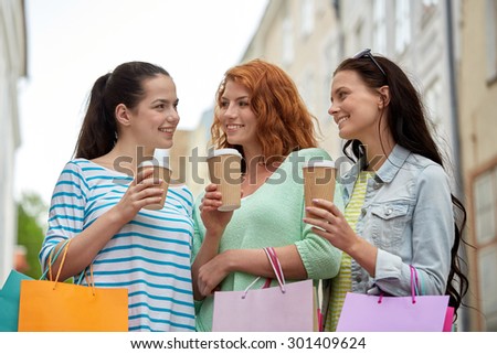 vacation, sale, takeaway drinks, leisure and friendship concept - smiling happy young women or teenage girls with shopping bags drinking coffee from disposable paper cups on city street
