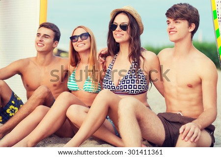friendship, sea, summer vacation, water sport and people concept - group of smiling friends wearing swimwear and sunglasses with surfboards on beach