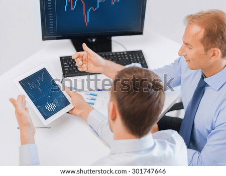 business, money and office concept - businessmen with notebook and tablet pc discussing forex chart on meeting