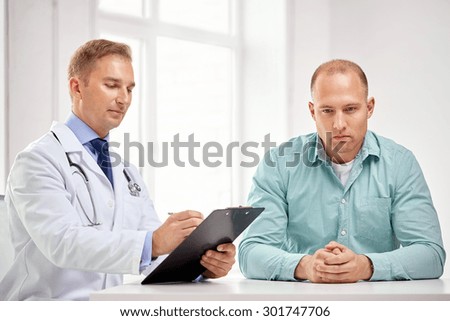 medicine, health care, people and prostate cancer concept - male doctor with clipboard and patient meeting and talking at hospital