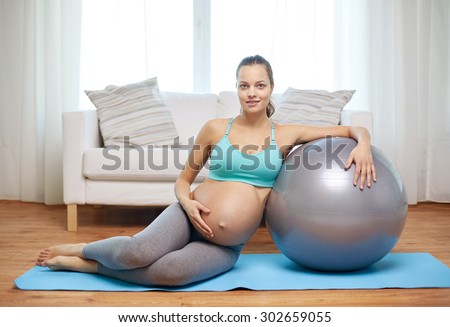 pregnancy, sport, fitness, people and healthy lifestyle concept - happy pregnant woman exercising with fitball at home