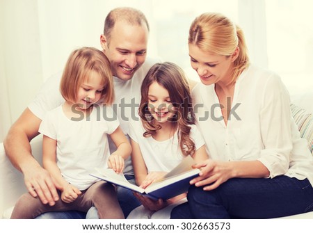 family, children and home concept - smiling family and two little girls with book at home