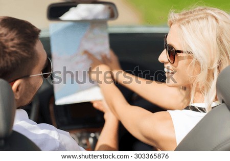 road trip, travel, leisure, couple and people concept - happy man and woman driving in cabriolet car with map