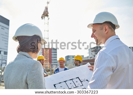 construction, architecture, business, teamwork and people concept - happy architects with blueprint at building site