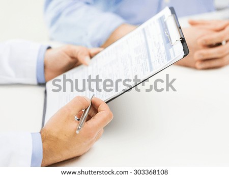 medicine, health care, people and prostate cancer concept - close up of f male doctor and patient hands with clipboard