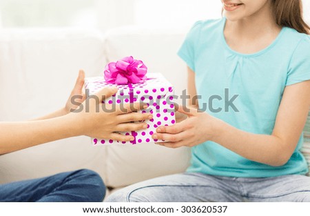 people, children, holidays, friends and friendship concept - close up of happy little girls with birthday present sitting on sofa at home