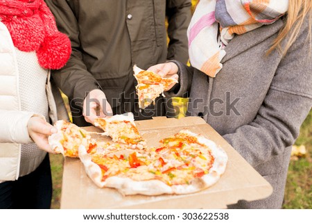 friendship, junk food and people concept - close up of friends hands eating pizza from cardboard box outdoors