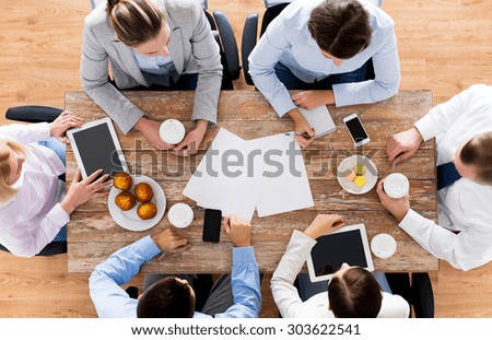 business, people, break and team work concept - close up of creative team meeting and drinking coffee with muffins during lunch in office